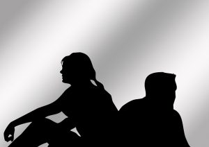 A silhouette of a man and a woman not facing each other trying to figure out what to do to heal from a breakup.