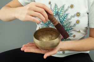 A woman using a Tibetan bowl to raise her vibration.