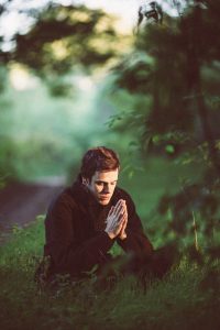 A young man praying in a beautiful garden