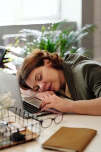 A woman at work that has fallen asleep from exhaustion in need of finding ways to make herself happier.
